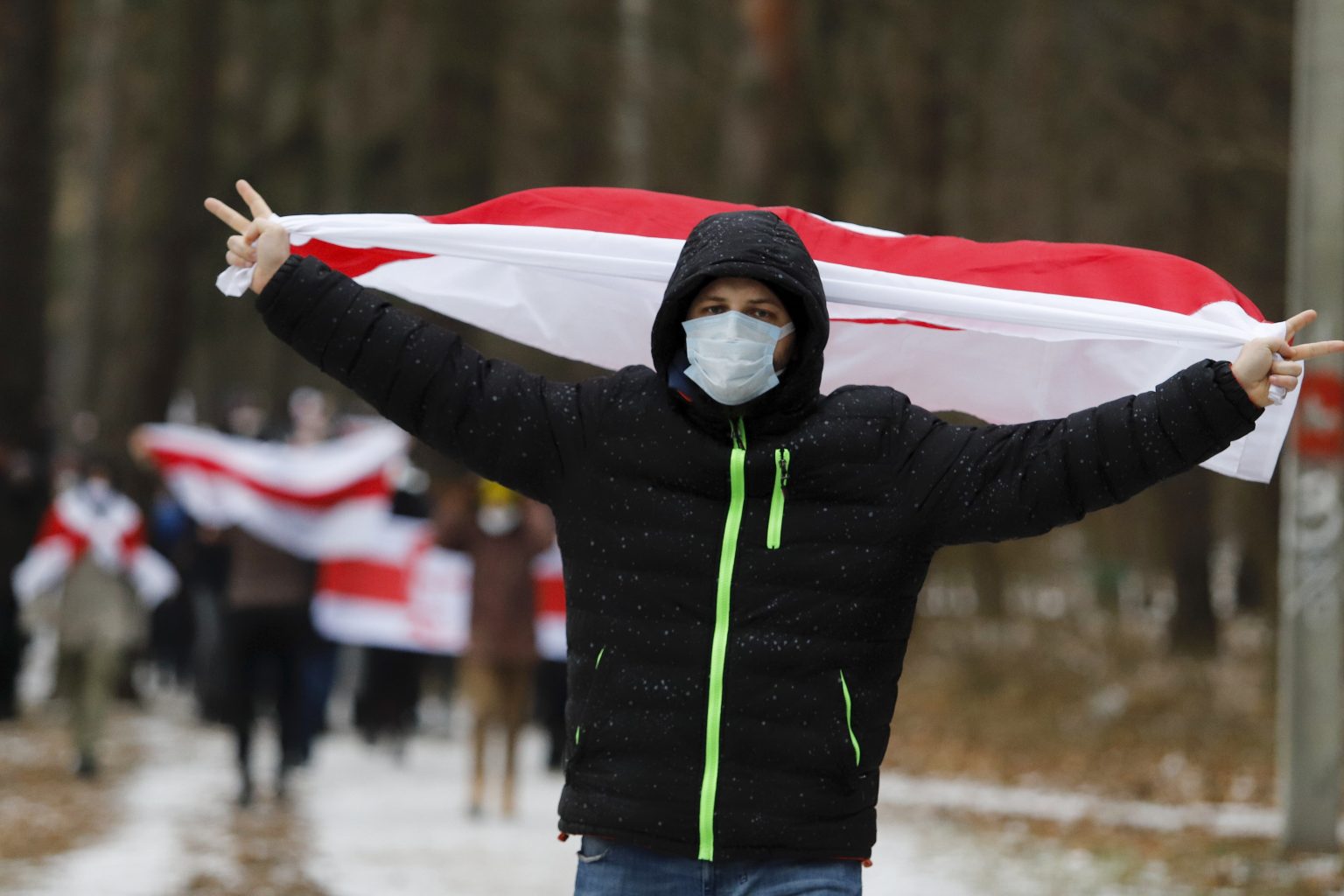 Demonštranti so starými bieloruskými národnými zástavami pochodujú počas opozičného protestného zhromaždenia proti výsledkom prezidentských volieb v bieloruskom Minsku v nedeľu 13. decembra 2020.
