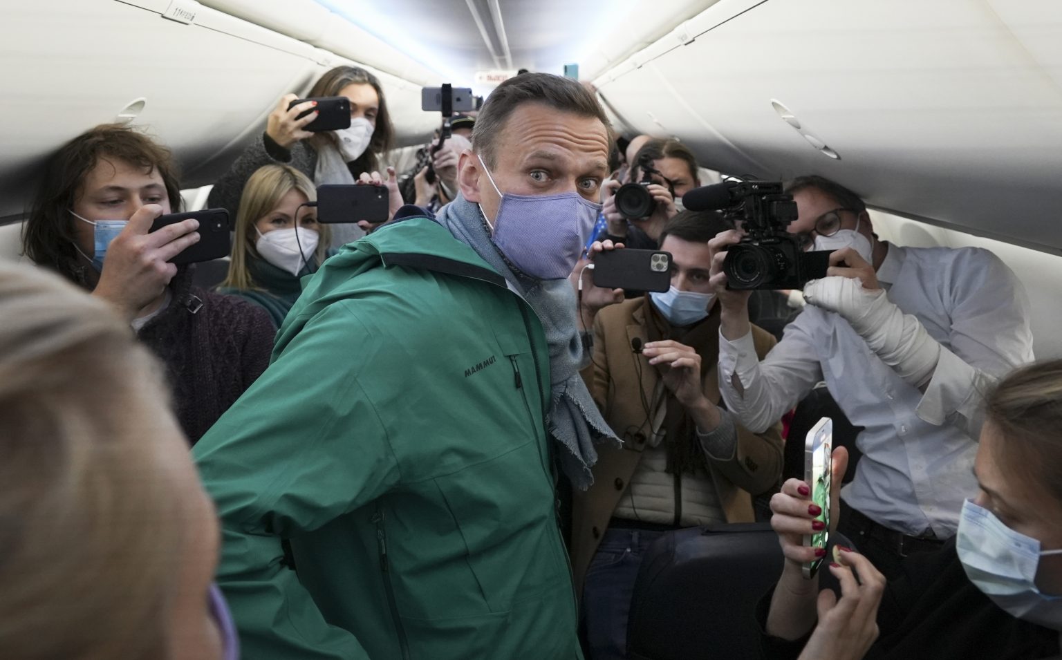 Ruský opozičný líder Alexej Navaľnyj (uprostred) stojí v obkľúčení novinárov na palube lietadla Boeing 737-800 ruskej leteckej spoločnosti Pobeda pred odletom z Letiska Berlín Brandenburg (BER) v Schönefelde v nedeľu 17. januára 2021. Foto:TASR/AP