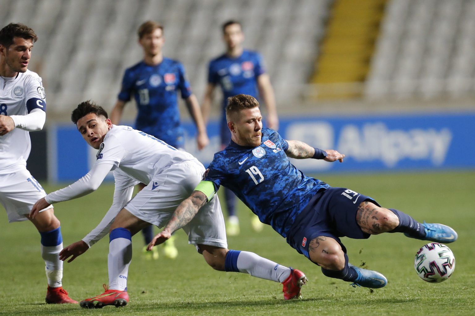 Juraj Kucka (vpravo) a cyperský hráč Loizos Loizo (druhý zľava) v zápase H-skupiny kvalifikácie MS 2022 vo futbale Cyprus - Slovensko v Nikózii 24. marca 2021. Foto: TASR/AP