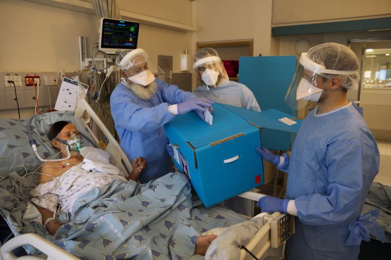 Pacient s ochorením COVID-19 odovzdáva svoj hlas do prenosnej urny v nemocnici v Tel Avive počas predčasných parlamentných volieb v Izraeli v utorok 23. marca 2021. Foto: TASR/AP