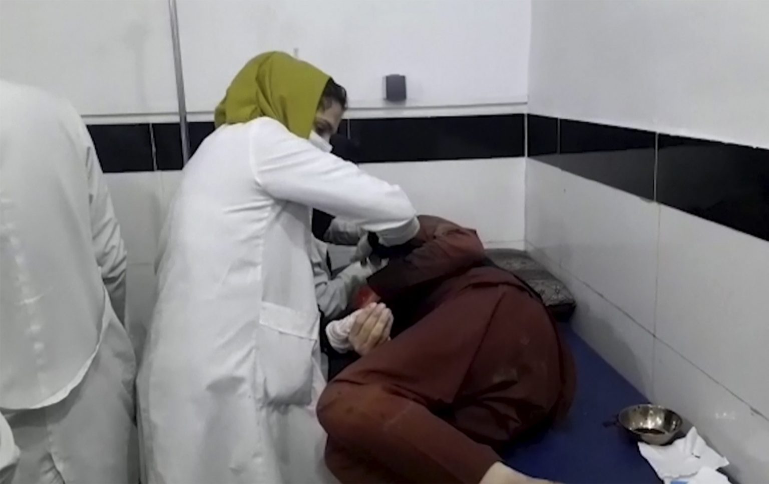 Na videosnímke zdravotníčka ošetruje osobu neďaleko zranenú počas výbuchu pri letisku v Kábule. Foto: TASR/AP