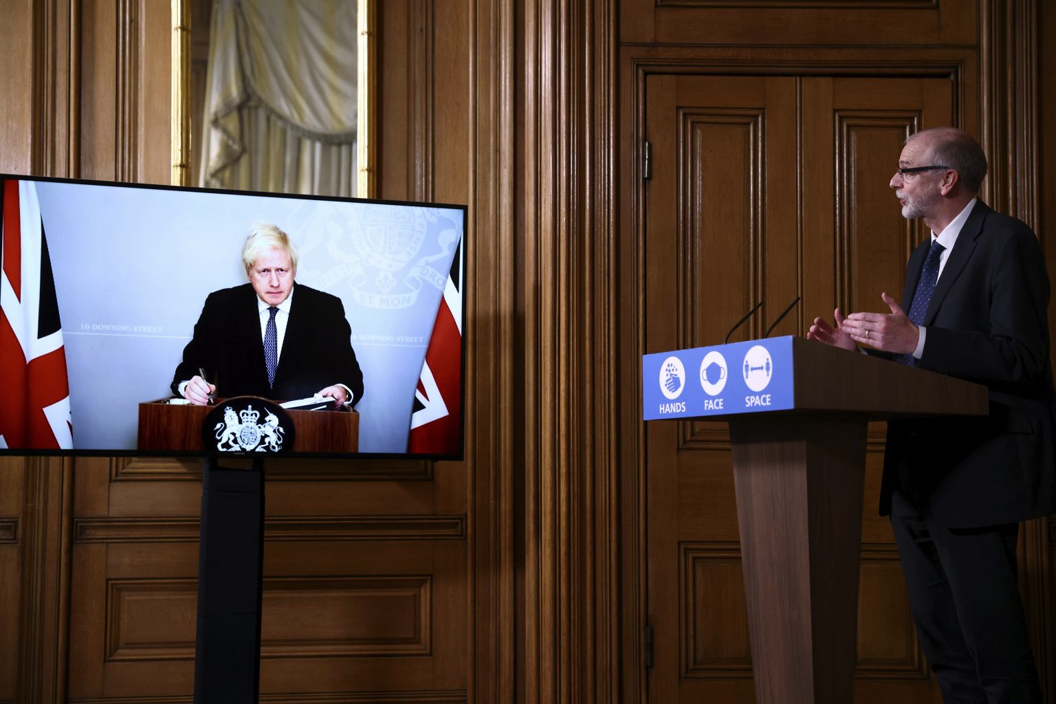 Britský premiér Boris Johnson na monitore počas tlačovej konferencie ohľadne koronavírusovej pandémie s riaditeľom Oxfordskej vakcinačnej skupiny Andrewom Pollardom (vpravo) na Downing Street 10 v Londýne 23. novembra 2020. Foto: TASR/AP