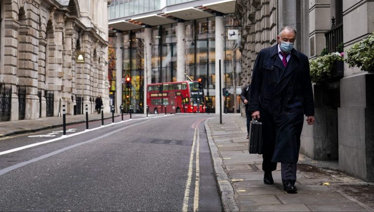 Muž kráča prázdnou ulicou v londýnskej finančnej štvrti City v pondelok 13. decembra 2021. Foto: TASR/AP