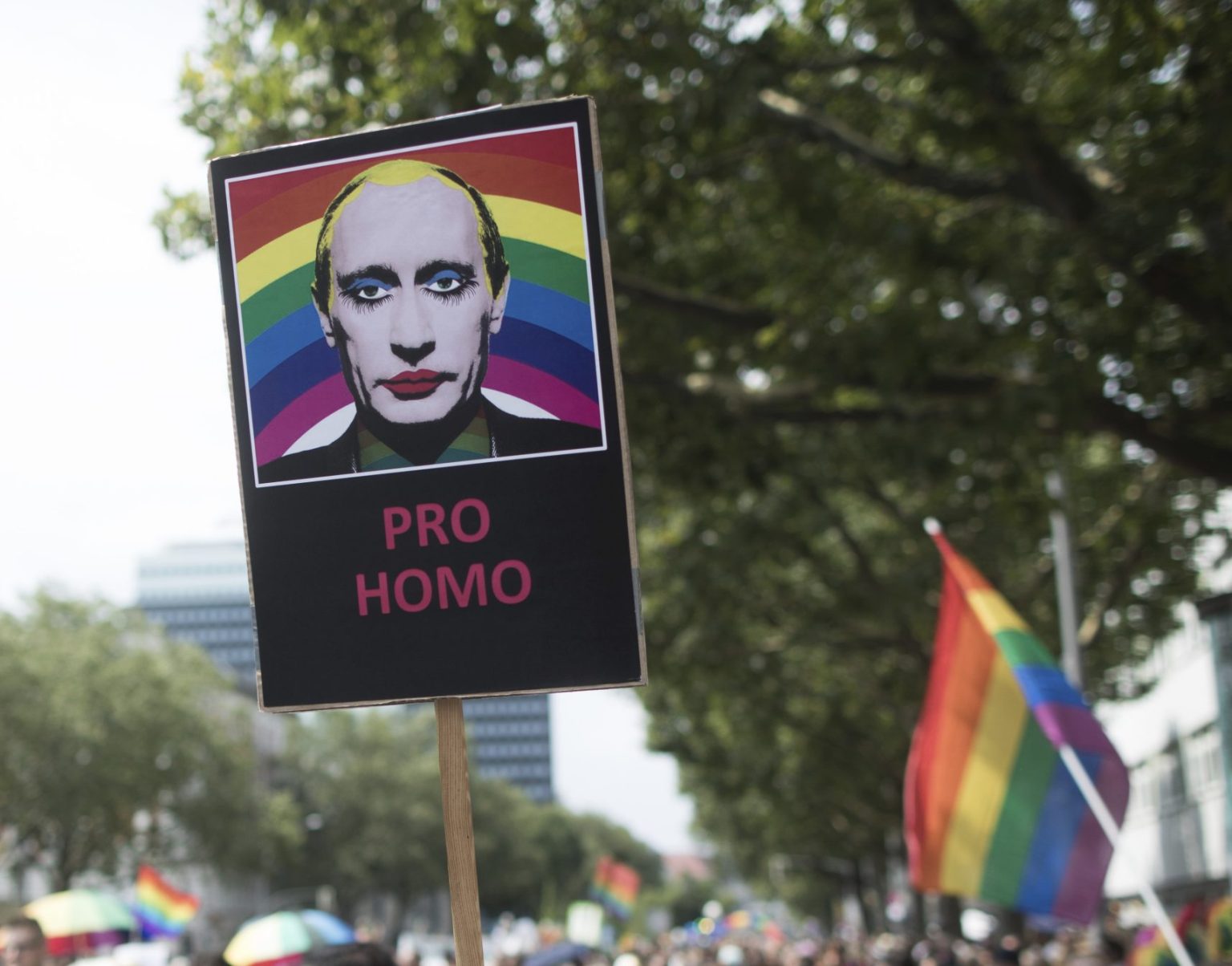 Účastníčka nesie transparent s podobizňou ruského prezidenta Vladimira Putina v pozadí s dúhovými farbami počas pochodu za práva gejov. Foto: TASR/AP