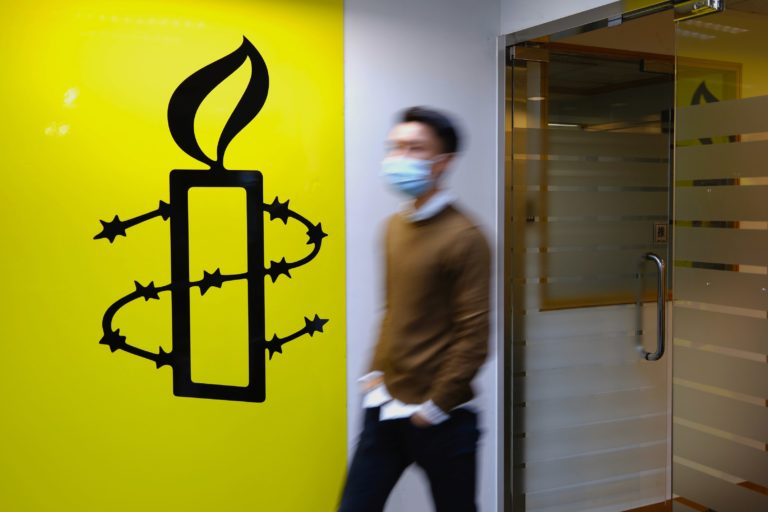 Muž kráča okolo loga kancelárie Amnesty International v Hongkongu 25. októbra 2021. Foto: TASR/AP