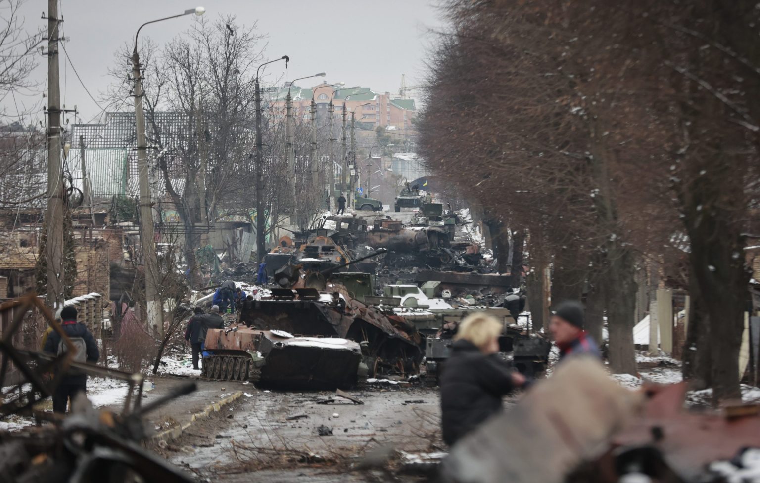 Ľudia si prezerajú vraky ruských vojenských vozidiel na ceste v meste Buča na západ od Kyjeva. Foto: TASR/AP