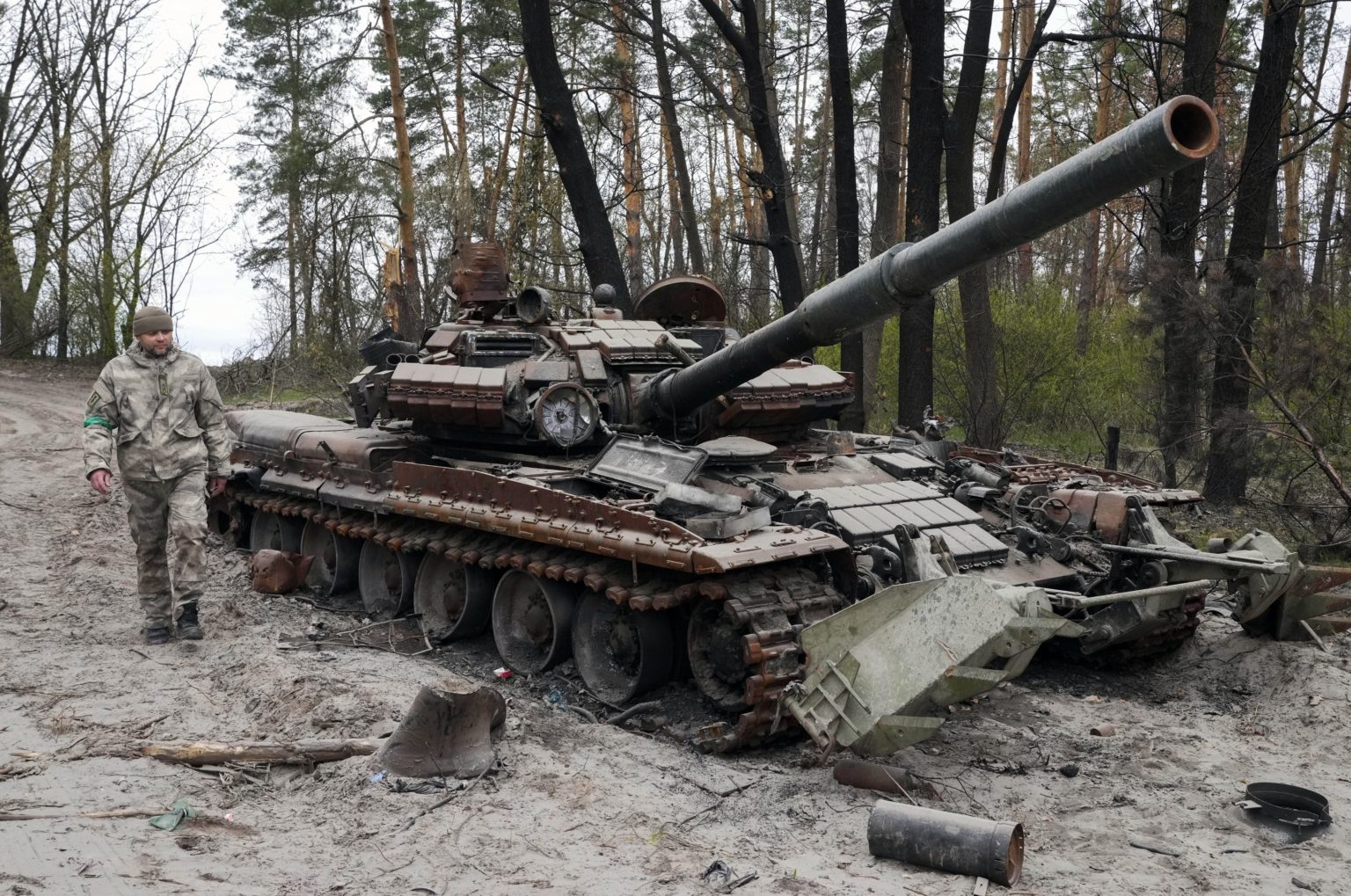 Ukrajinský vojak kráča okolo ruského tanku po bojoch počas 55. dňa ruskej invázie na Ukrajinu 19. apríla 2022 v ukrajinskej obci Moščun. Foto: TASR/AP