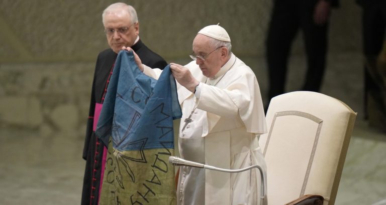 Pápež František z ukrajinskou vlajkou, ktorú mu poslali z mesta Buča. Foto: TASR/AP