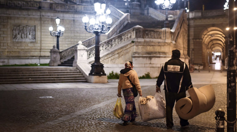 Bezdomovci kráčajú po prázdnej ulici  v talianskej Bologni 23. marca 2020. Foto: TASR/AP