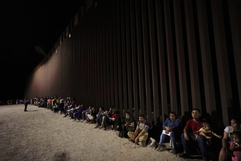 Migranti, ktorí prišli z Mexika, čakajú pri hraničnom múre neďaleko mesta Yuma v americkom štáte Arizona v utorok 23. augusta 2022. Foto: TASR/AP
