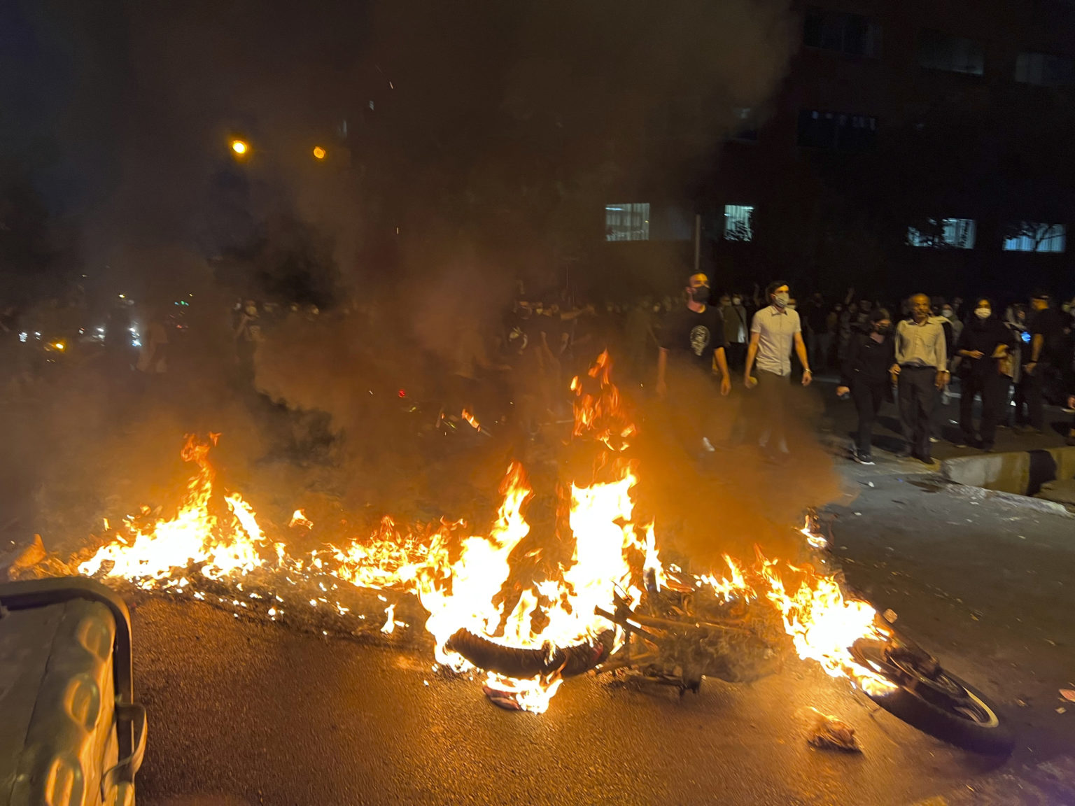 Policajný motocykel horí počas protestu proti smrti mladej iránskej ženy Mahsá Amíníovej v centre Teheránu. Foto: TASR/AP