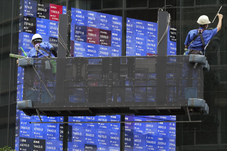 Pracovníci utierajú okná pred elektronickou tabuľou zobrazujúcou kľúčový tokijský index Nikkei 225 v Tokiu v utorok 23. augusta 2022. Foto: TASR/AP