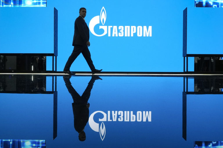 Na archívnej snímke zo 14. septembra 2022 muž kráča okolo loga ruského štátneho energetického giganta Gazprom. Foto: TASR/AP