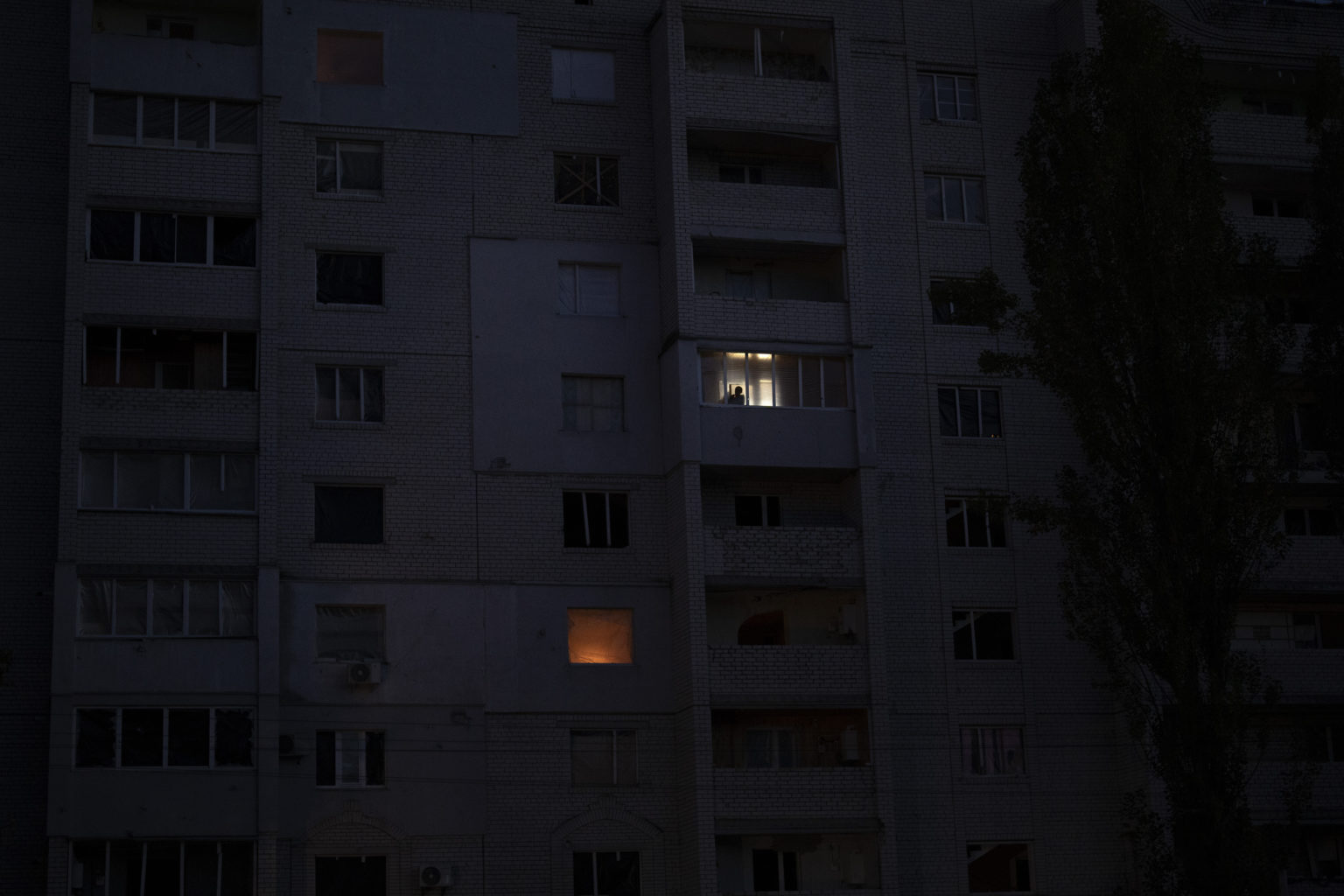 Muž sa pozerá z okna obytnej budovy zničenej počas bojov medzi ukrajinskými a ruskými silami v v Boroďanke na predmestí Kyjeva. Foto: TASR/AP