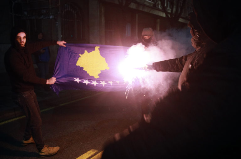 Maskovaní demonštranti pália kosovskú vlajku počas pochodu v srbskom Belehrade v pondelok 12. decembra 2022. Ilustračný záber. Foto: TASR/AP