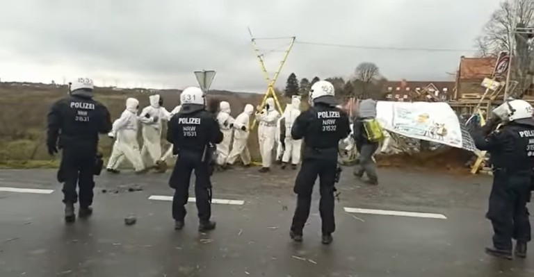 Aktivisti v Nemecku zablokovali cestu do obce, cez ktorú sa má rozšíriť baňa. Jeden sa prilepil k ceste