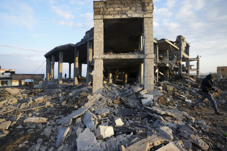 Ilustračná fotografia. Ľudia si prezerajú trosky zničenej budovy zasiahnutej izraelskými leteckými útokmi v meste Gaza. Foto: TASR/AP
