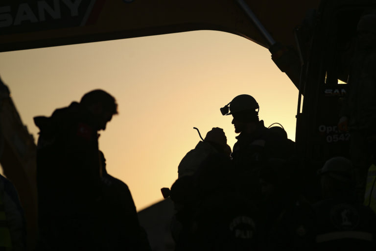 Tureckí hasiči stoja na sutinách budovy. Foto: TASR/AP