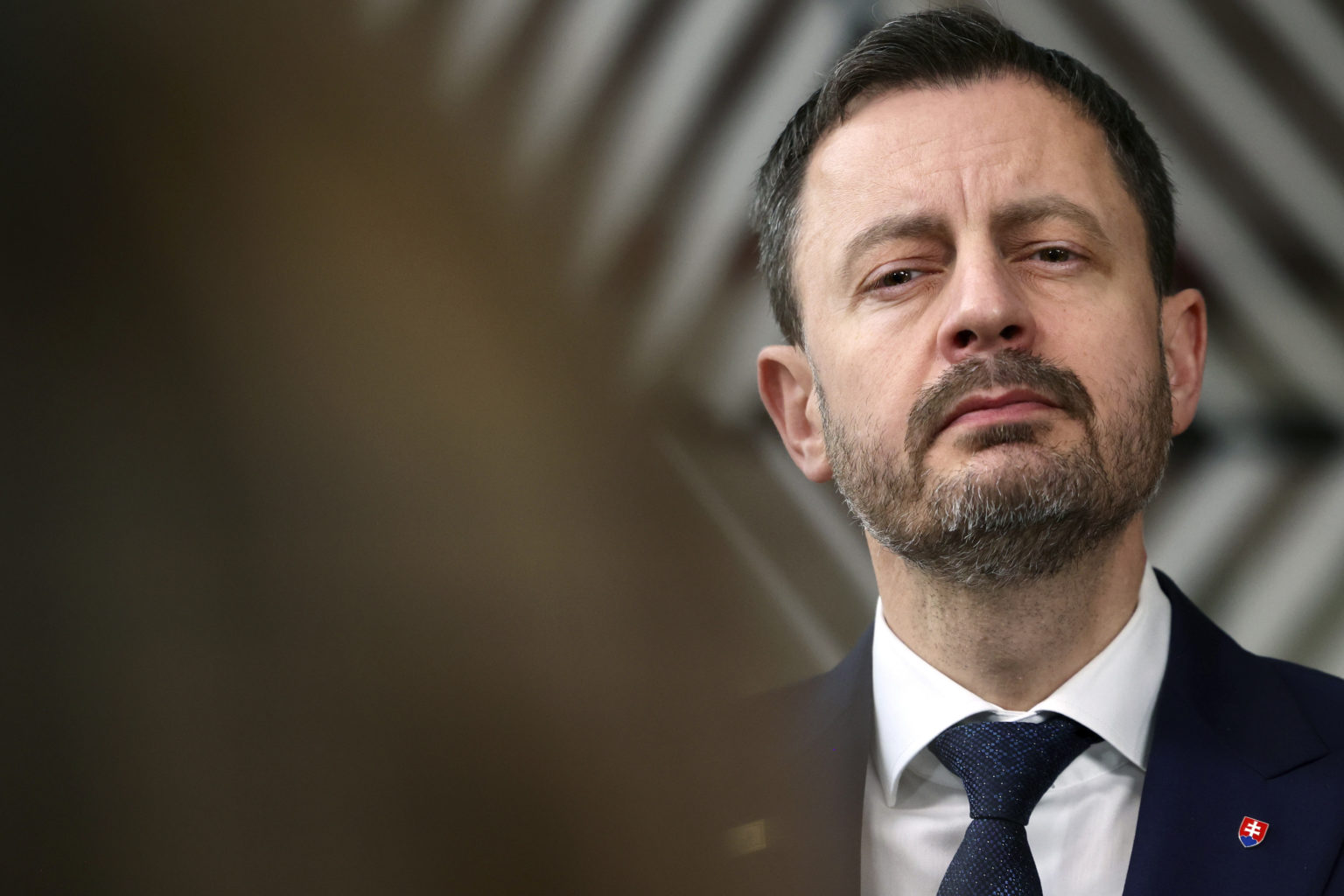 Slovenský premiér Eduard Heger  odpovedá na otázky novinárov počas príchodu na druhý a záverečný deň samitu EÚ v Bruseli v piatok 25. marca 2023. Foto: TASR/AP
