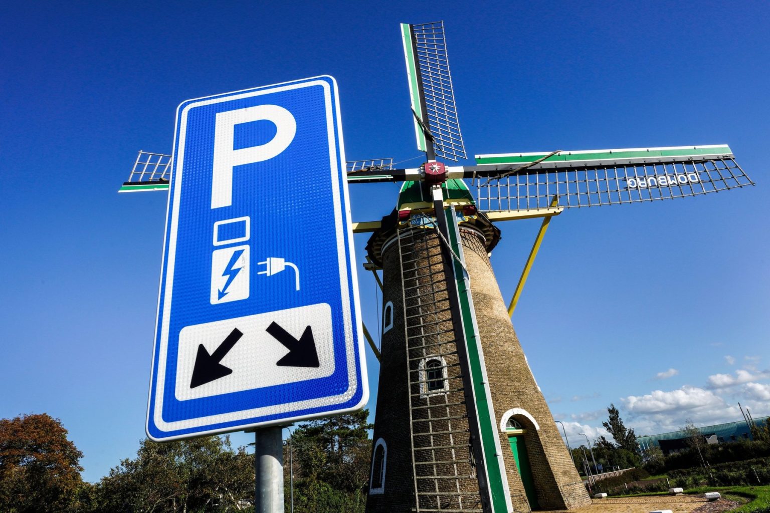 Parkovisko s nabíjacím bodom pre elektrické vozidlá pred historickým veterným mlynom z roku 1817 v Domburgu v Holandsku. Foto: Profimedia.sk