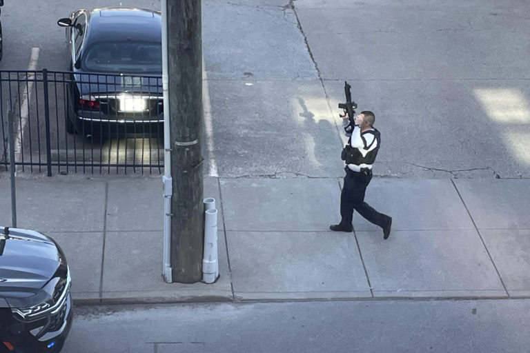 Policajt so zbraňou v ruke zasahuje počas streľby, ku ktorej došlo v budove banky  v centre amerického mesta Louisville v pondelok 10. apríla 2023. Foto: TASR/AP