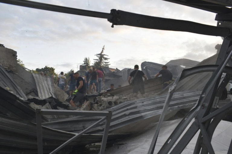 Ľudia odpratávajú trosky zo strechy zničenej reštaurácie RIA Pizza po ruskom raketovom útoku v meste Kramatorsk. Foto: TASR/AP