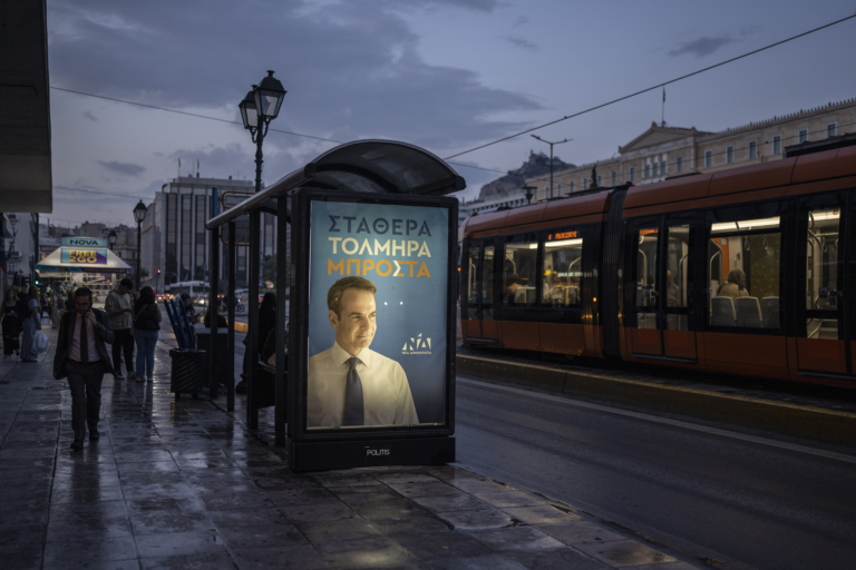 Muž kráča okolo volebného plagátu gréckeho premiéra a lídra gréckej strany Nová demokracia (ND) Kyriakosa Mitsotakisa 30. mája 2023 v Aténach. Foto: TASR/AP