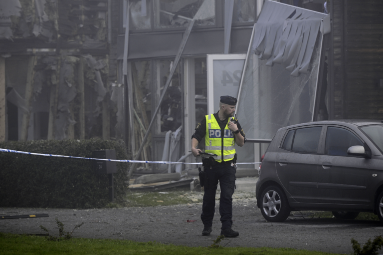 Policajt stojí na mieste silného výbuchu, ku ktorému došlo vo štvrtok skoro ráno 28. septembra 2023 v obytnej oblasti v Storvrete pri Uppsale vo Švédsku. Foto: TASR/AP