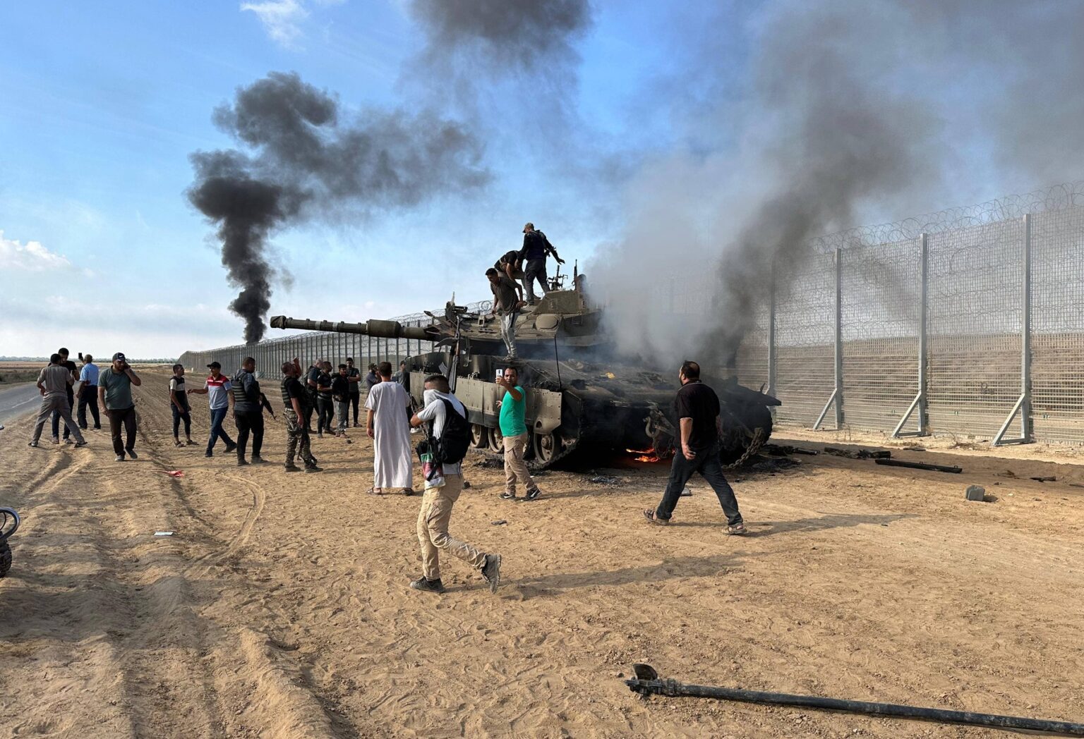 Palestínski bojovníci okolo zničeného izraelského tanku. Foto: Profimedia.sk