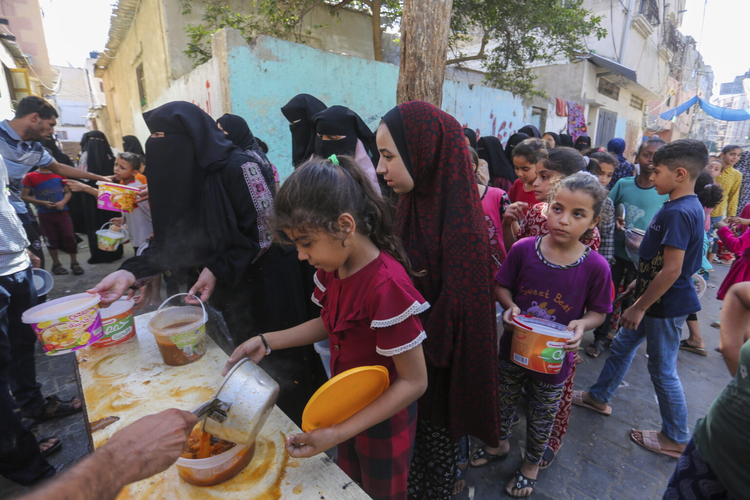 Palestínčania dostávajú jedlo počas distribúcie potravín v Rafahu, na juhu pásma Gazy v stredu 8. novembra 2023. Foto: TASR/AP