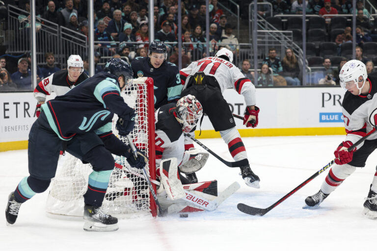 Na snímke vpravo slovenský obranca New Jersey Šimon Nemec, uprostred jeho spoluhráč v bránke Akira Schmid a vľavo obranca Seattle Kraken Ryker Evans v zápase hokejovej NHL Seattle Kraken - New Jersey Devils v noci na 8. decembra 2023. Foto: TASR/AP