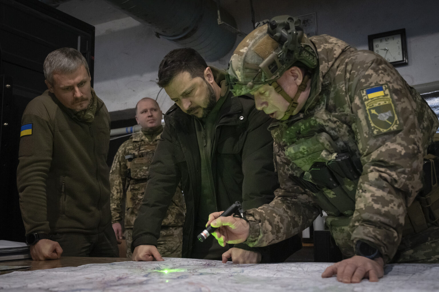 Ukrajinský prezident Volodymyr Zelenskyj (druhý vpravo), veliteľ ukrajinských pozemných síl Oleksandr Syrskij (vpravo) a zástupca vedúceho prezidentskej kancelárie Roman Mašovec (vľavo) sa pozerajú na mapu v blízkosti frontu v Charkovskej oblasti na východe Ukrajiny. Foto: TASR/AP   