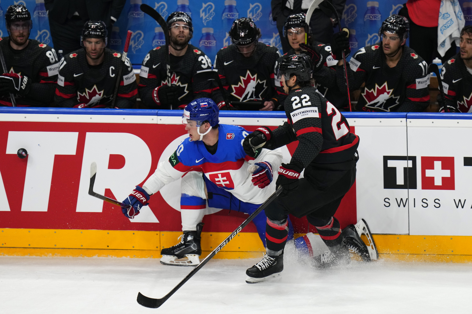 Slovenský hokejista Juraj Slafkovský (vľavo) a hráč Kanady Dylan Cozens bojujú o puk pri mantineli počas štvrťfinálového zápasu Kanada - Slovensko na 87. majstrovstvách sveta v ľadovom hokeji v Prahe vo štvrtok 23. mája 2024. Foto: TASR/AP