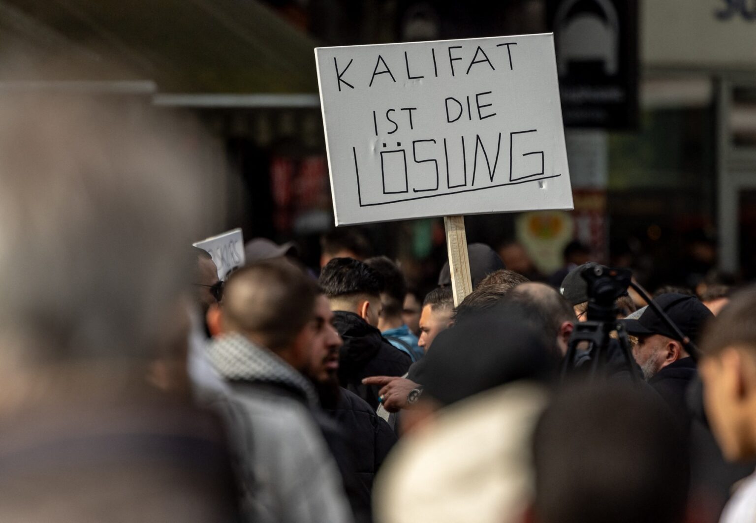 Účastníci islamistickej demonštrácie v Hamburgu držia plagát s heslom "Riešením je kalifát", 27. apríla 2024. Zdroj: Profimedia
