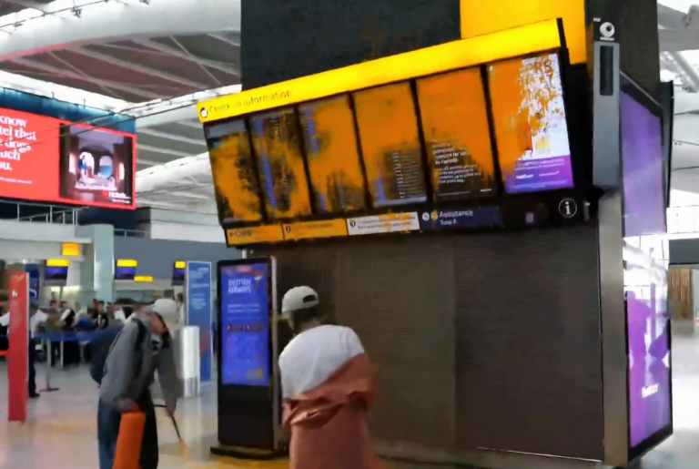 Aktivistky klimatickej skupiny Just Stop Oil striekajú oranžovú farbu na tabuľu odletov na londýnskom letisku Heathrow. Reprofoto: Just Stop Oil/X