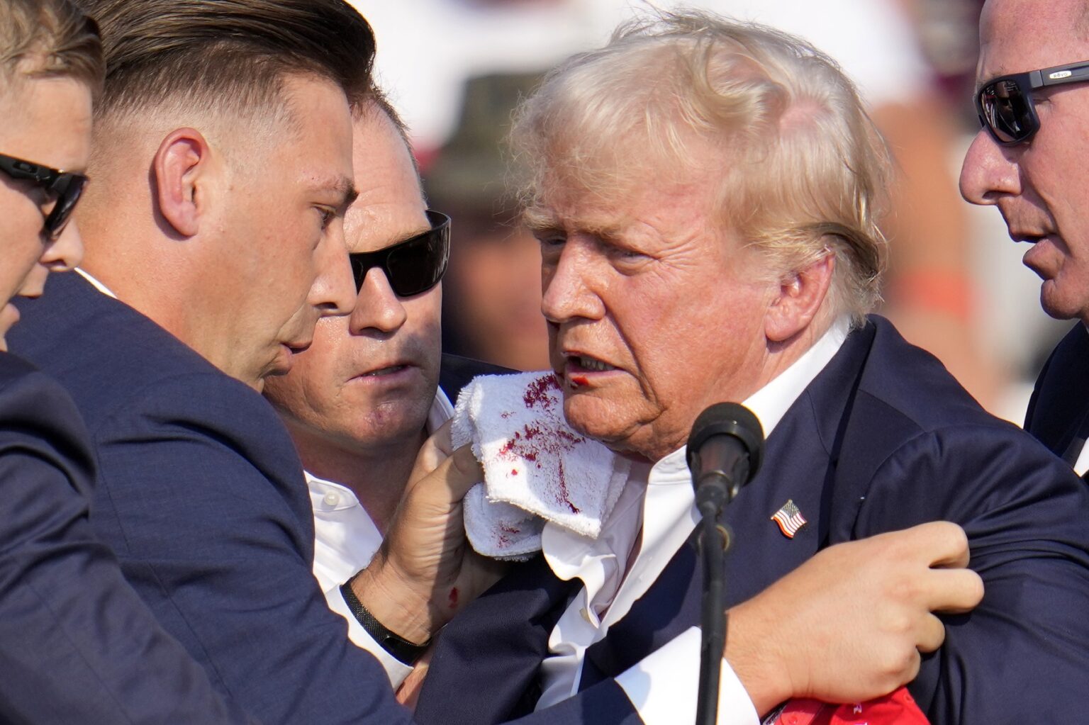 Republikánsky kandidát na prezidenta, bývalý prezident Donald Trump, po streľbe v sobotu 13. júla 2024 obklopený americkou tajnou službou na predvolebnej akcii. Butler, Pensylvánia. ČTK / AP / Gene J. Puskar/ Profimedia