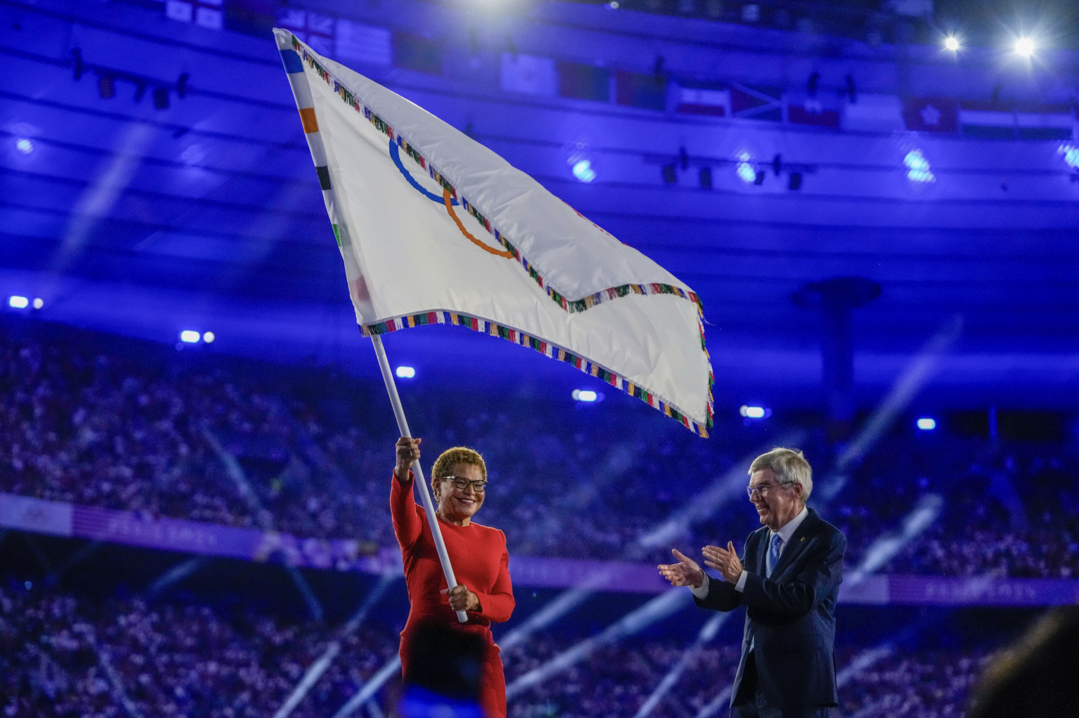 Starostka Los Angeles Karen Bassová (vľavo) máva olympijskou zástavou vedľa prezidenta Medzinárodného olympijského výboru Thomasa Bacha počas záverečného ceremoniálu XXXIII. letných olympijských hier na štadióne Stade de France v Paríži.Foto: TASR/AP
