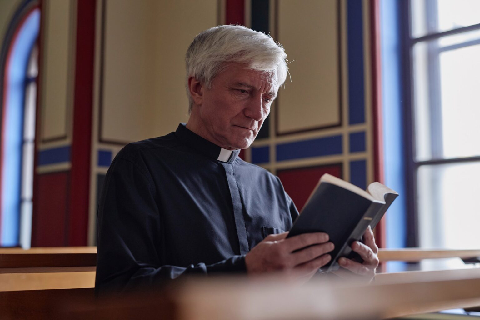 Starší katolícky kňaz pri čítanie Biblie. Foto: Profimedia.sk