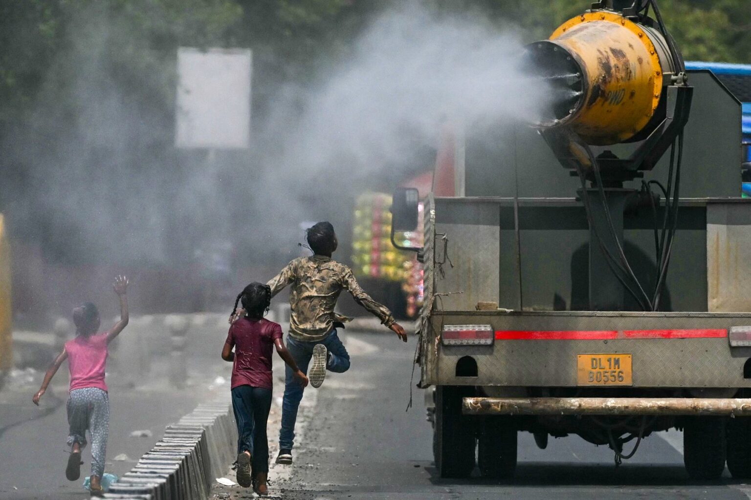 Deti bežia za nákladným autom, ktoré rozprašuje vodu po ulici počas horúceho letného dňa v Naí Dillí 28. mája 2024. Zdroj: Arun SANKAR / AFP / AFP / Profimedia