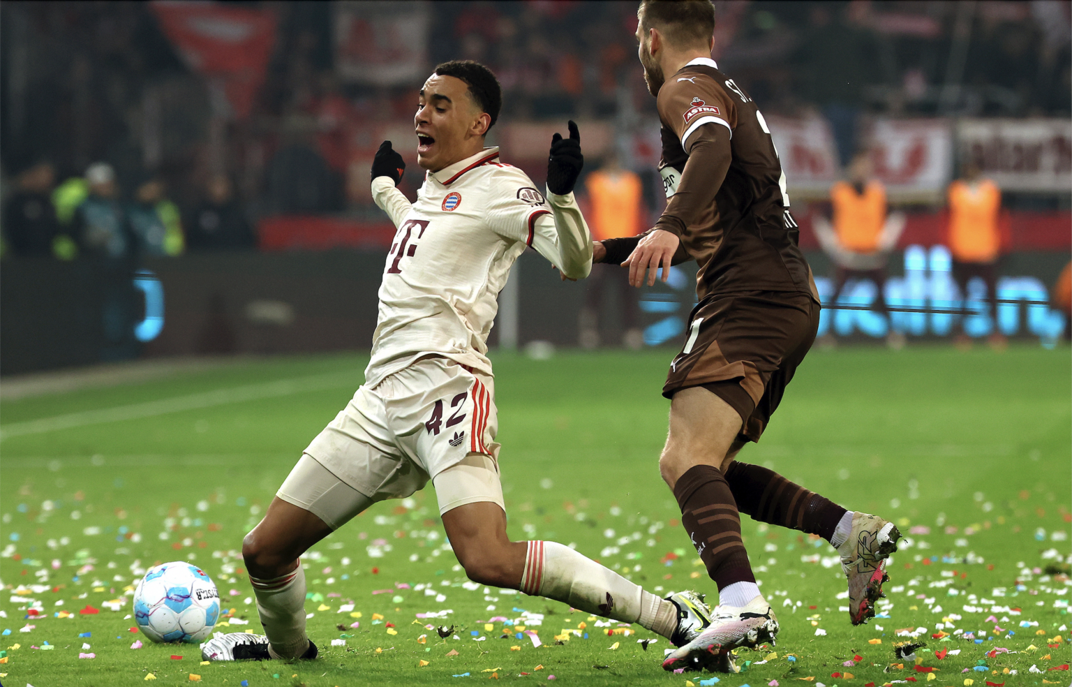 Jamal Musiala z Bayernu (vľavo) a Lars Ritzka zo St. Pauli (vpravo) bojujú o loptu počas futbalového zápasu nemeckej Bundesligy. Foto: TASR/AP