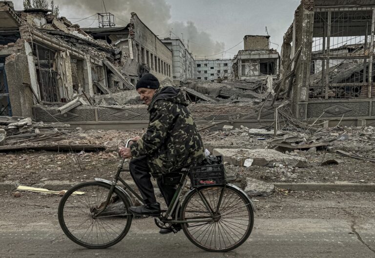 Muž jazdí na bicykli pred poštovou kanceláriou, ktorá bola 7. novembra 2024 zničená ruským náletom v Kurachove v Doneckej oblasti na Ukrajine. Foto: ČTK / AP / Anton Shtuka