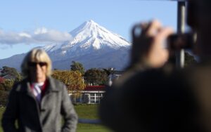 A man photographs his wife with Mount Taranaki in the background in New Plymouth, New Zealand. Photo: Dita Alangkara/AP/CTK