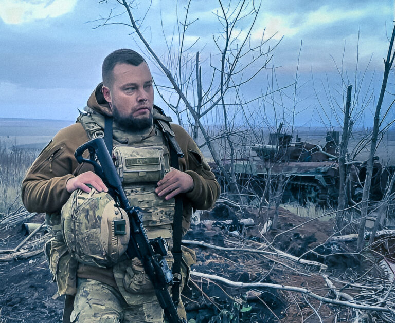 Alexej Miľčakov v bojovej zóne na okupovanom území Ukrajiny v januári 2025, v pozadí zničená vojenská technika. Foto: Alexej Miľčakov/Daniel Halaj