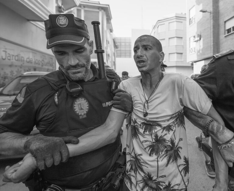 Policajti eskortujú osobu z protiprisťahovaleckej demonštrácie. Foto: Olmo Blanco/Getty Image
