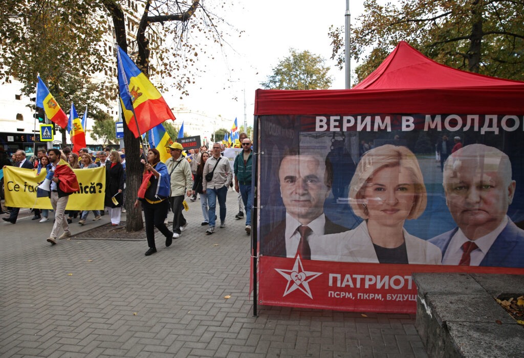 Stúpenci Strany akcie a solidarity vedľa pútača Vlasteneckého bloku Moldavska. Foto: Vladislav Culiomza/Reuters