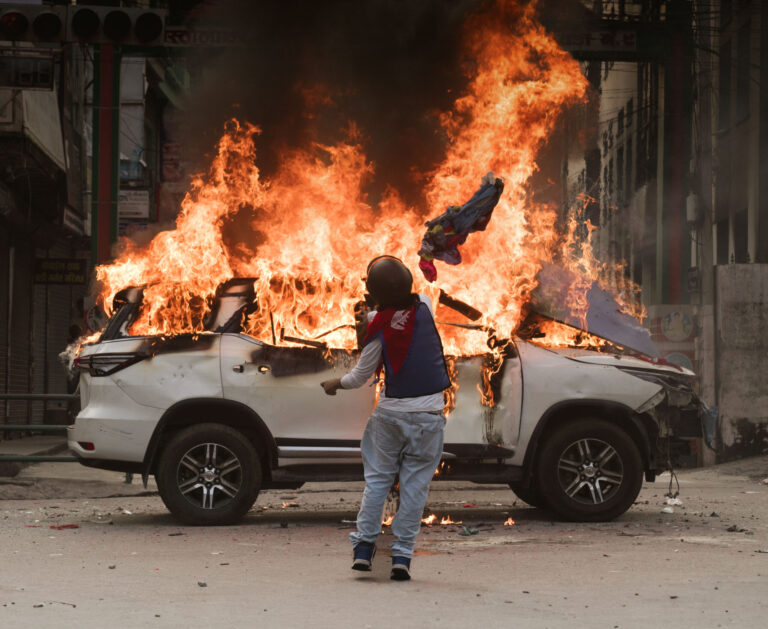 Ein Demonstrant, der sich in die nepalesische Nationalflagge gehüllt hatte, zündete ein Regierungsfahrzeug in Mahendrapool in Pokhara, Nepal, an. Foto: Getty Images