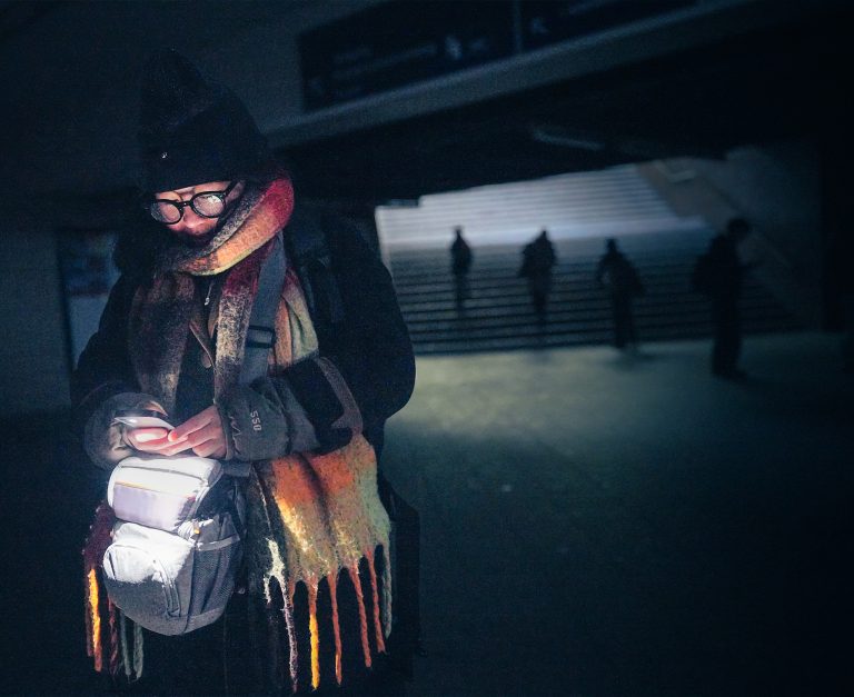 Eine Frau aus Berlin läuft nach einem Stromausfall mit dem Licht ihres Handys durch den Bahnhof Wannsee. Foto: Michael Kappeler/picture alliance via Getty Images