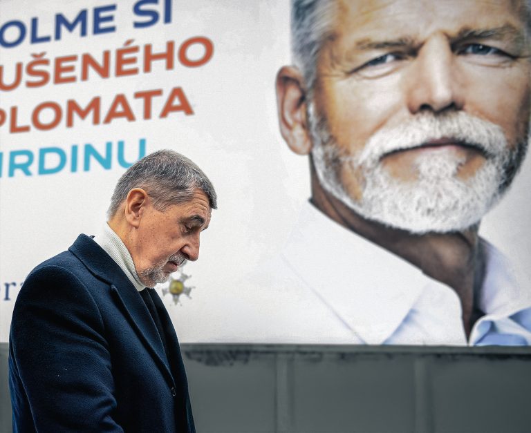 Andrej Babis in front of a poster of Petr Pavel.