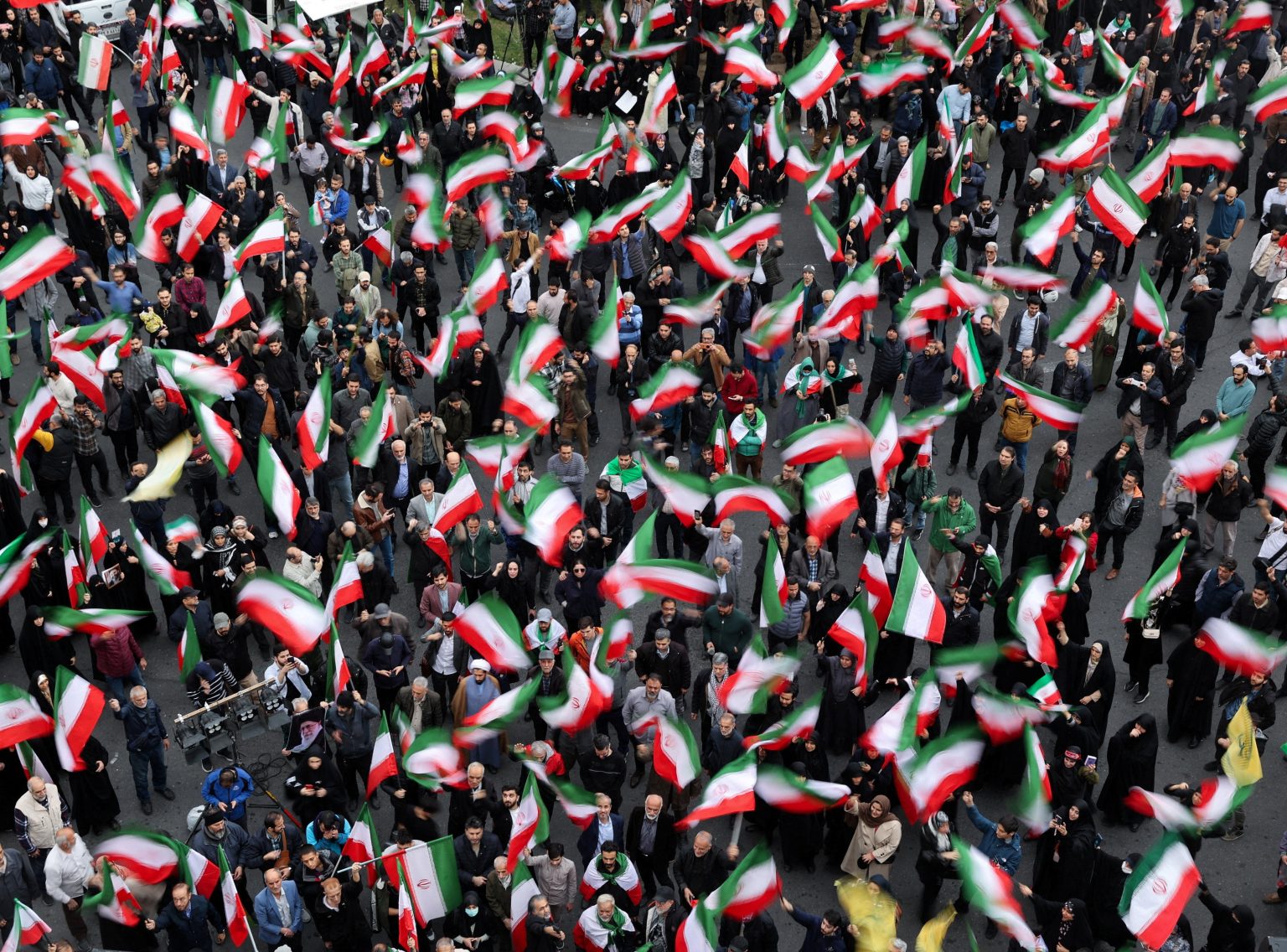 A crowd waves Iranian flags at a public gathering. Photo: Majid Asgaripour/WANA/Reuters
