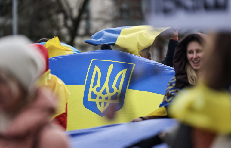 Ľudia nesú ukrajinské vlajky počas protestu pri sídle Organizácie Spojených národov. Foto: REUTERS/Pierre Albouy